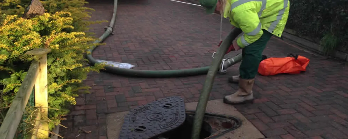 Septic tank cleaning technician servicing a septic tank with a vacuum hose in Cherry Hill, NJ