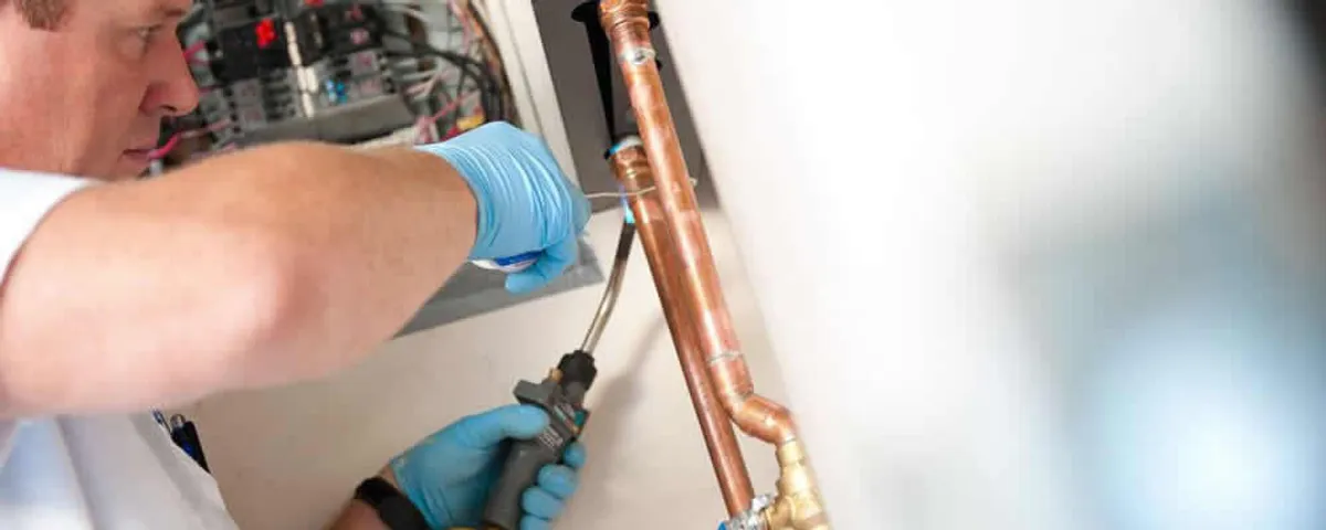 Water heater repair technician testing copper pipe connections and controls in Cherry Hill, NJ